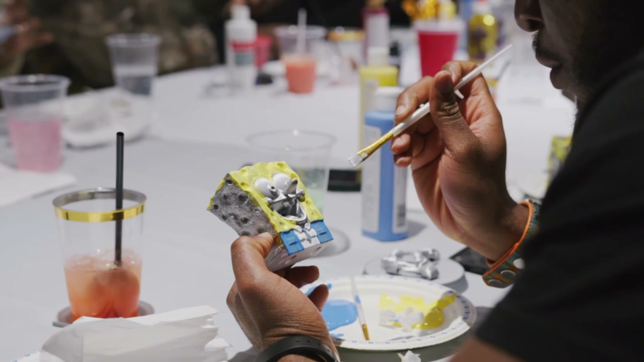 A brush painting a Square Buddy figurine during a paint night