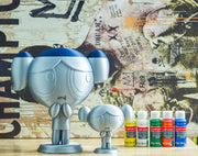 With paints: unpainted Pigtail Pal samples beside paint pots. Samples shown; not a complete-kit photograph.